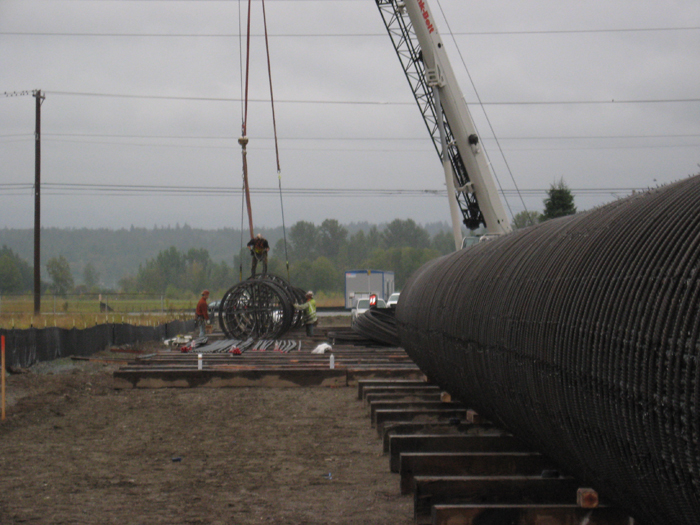Workers prepare steel rebar cages for bridge foundation shafts